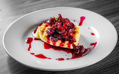 Halloumi cheese frying with cherry in plate on black wooden table