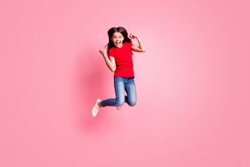 Fototapeta na wymiar Full size photo of delighted kid girl jump raise fists wear casual style outfit isolated over pink color background