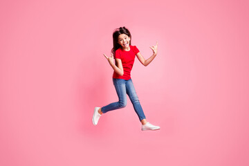 Fototapeta na wymiar Full size photo of crazy kid girl jump show horned symbol wear red t-shirt denim isolated over pastel color background