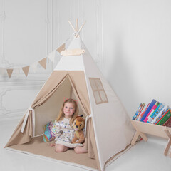 a girl plays with toys in a teepee