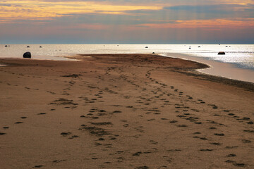 footprints on the sand spit at sunset time on the sea