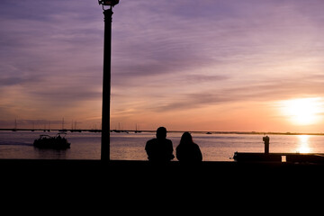 Silhouette of a couple in love on the waterfront in the city of Faro. colorful sunset on the beach..