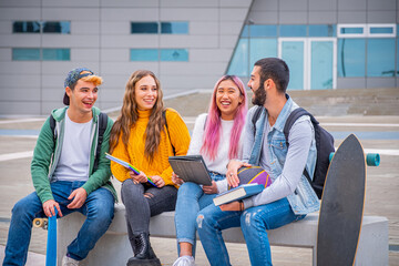 Multiethnic students joking and talking sitting on the bench together outdoors in a university -...