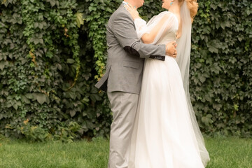 Fototapeta premium newlyweds hug in the park, the bride and groom hold hands in the green park.