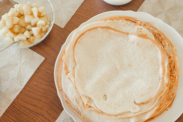 Pancake baking process. Ready-made pancakes on a white plate.