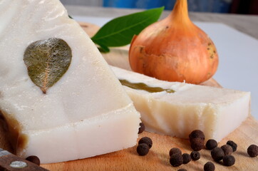 Salted lard with bay leaves and onion on the kitchen board. Salted homemade lard