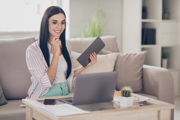 Photo of young business lady hold tablet finger chin wear eyeglasses shirt in home workstation indoors