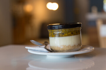 delicious and nice colorful dessert in a jar on a plate and with a spoon, wood table, food