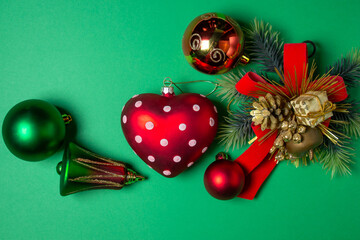Christmas decorations on a green background. Red and green Christmas balls. Christmas tree toys. Celebratory decorations.