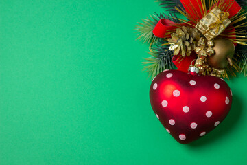 Christmas decorations on a green background. Christmas tree toy in the form of a heart. Celebratory decorations.