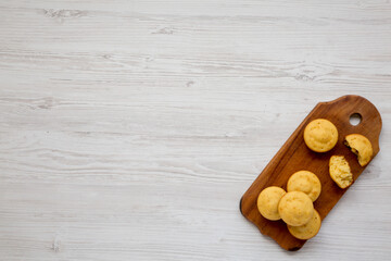 Homemade Cornbread Muffins on a rustic wooden board on a white wooden background, top view. Flat lay, overhead, from above. Copy space.