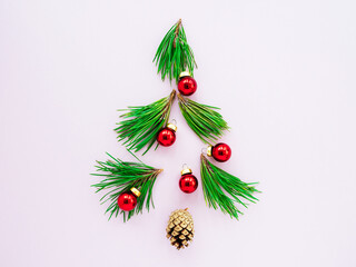 Christmas tree branches and red toys on a pink background, flatly, top view.