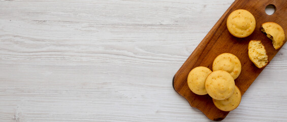 Obraz na płótnie Canvas Homemade Cornbread Muffins on a rustic wooden board on a white wooden background, top view. Flat lay, overhead, from above. Space for text.
