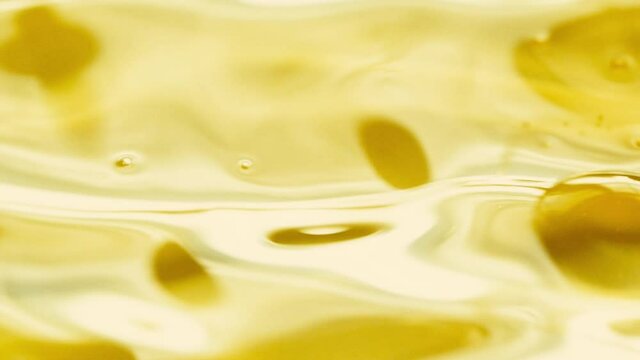 Close-up pouring golden olive oil liquid in slow motion, healthy food background