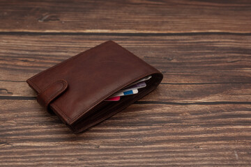 Closed men's brown wallet on a wooden brown background with business cards