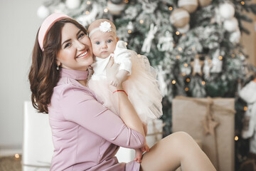 Fototapeta premium Young mother and her little baby daughter on christmas background