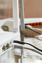 Two white wireless routers on a glass table connected by cables to the Internet. Close-up