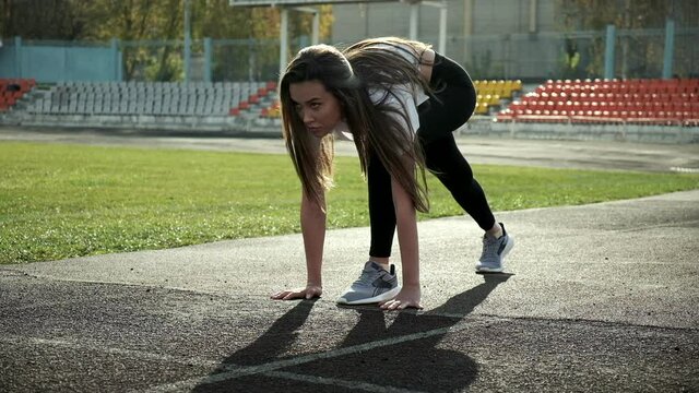 young asian pretty woman preparing to run at stadium. slim fitness runner in sportswear starts running from block on stadium track. fit sportive female in starting position. sports, healthy lifestyle