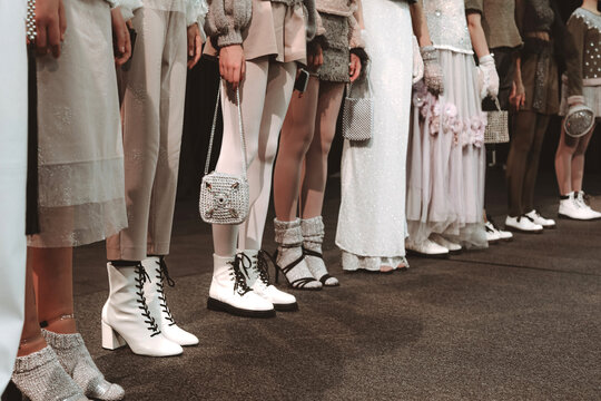 Cropped figures of models in trendy designer outfits with handbags on the backstage of Fashion Week. Fashion shot