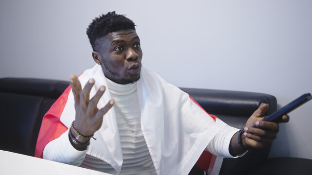 Young black man man with polish flag watching game on tv. Disappointed face expression and gesticulation. High quality photo