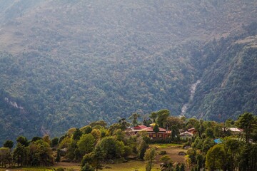 Fototapeta na wymiar Beautiful biddhism monastery surrounded with green trees and amazing high mountains on the background. Nepalese Himalaya.