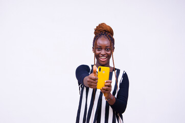 young lady holding a smart phone and smiling while doing a thumbs-up