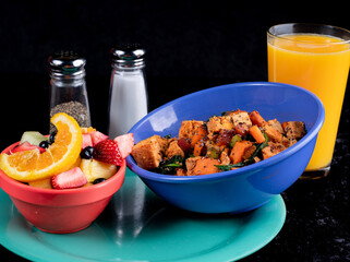 Image of a healthy breakfast with a tofu sweet potato scramble, fruit and orange juice.