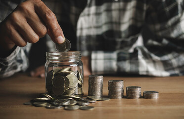 Business man putting the money in glass jar to saving,financial,accounting concept.