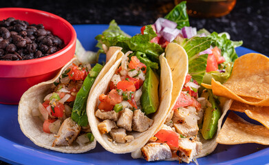 A delicious plate of tacos with a flavorful beverage, beans and salad.