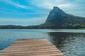 Pier against backdrop of mountains and forest. Forest scene and wooden pier on mountain lake, Burabay in Kazakhstan