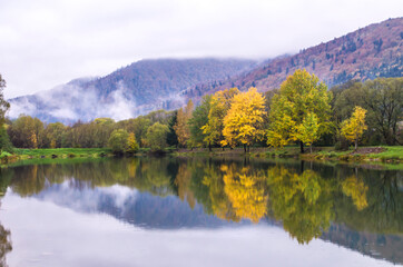 Autumn park with pond. Lake reflections of fall foliage.