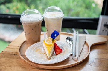 Lemon cake with biscuit and ice coffee on wooden tray
