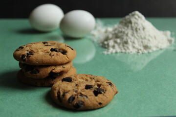 kitchen still life cooking process homemade chocolate cookies with chocolate drops in the background flour and chicken eggs lie on a green grass mirror background with a reflection of copy space