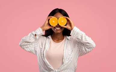 Skin detox and beauty concept. Gorgeous African American lady covering both eyes with orange halves...