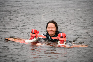 Obraz premium happy young woman swims in the water in vest with bright wakeboarding board