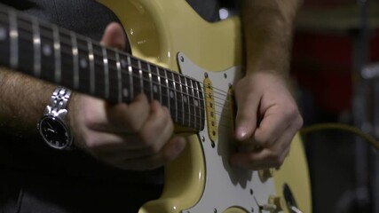 Close up man's hands playing yellow electric guitar
