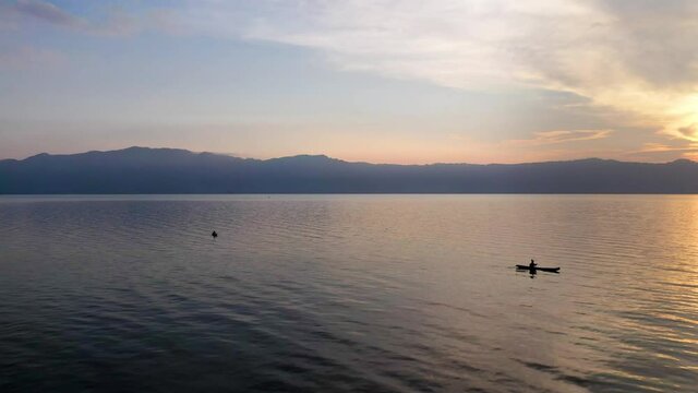 Aerial view over man rowing boat on Lake Toba at sunset in North Sumatra, Indonesia