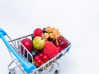 Mini grocery cart filled with fresh vitamin berries isolated on white background