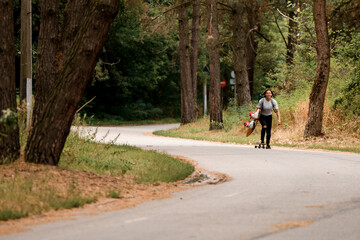 Obraz premium active sporty young woman rides on skateboard with wakeboard in her hand