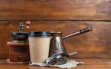 still life: metal scoop, vintage cezve and coffee grinder on rustic wooden table spilled with roasted beans