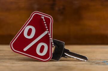 red percent sign and home key on wooden background . real estate concept