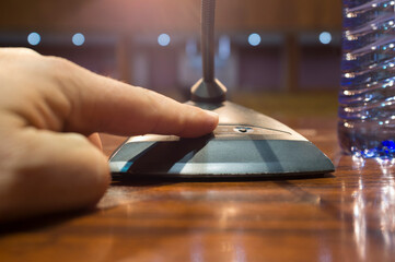 Obraz premium Speaker finger is about to press on-off button of a table conference microphone