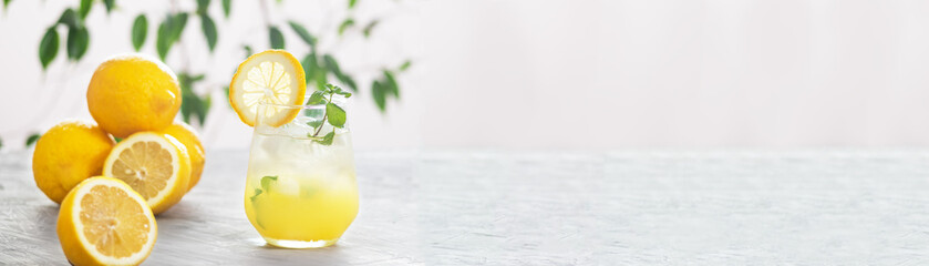 Citrus iced lemonade in the glass with lemon slice and mint leaves decoration on marble table on natural background