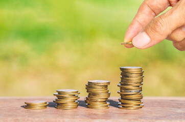 business man hand put golden coin stack growth up isolated on green blur nature background. money saving, financial growing, business startup, economy budget and investment concept.