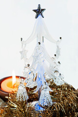 Close-up view of a small glass Christmas tree with a candle lighted on.