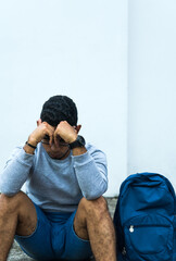 Fototapeta premium young man sitting on the sidewalk of a street with a lost look of sadness, depression concept.