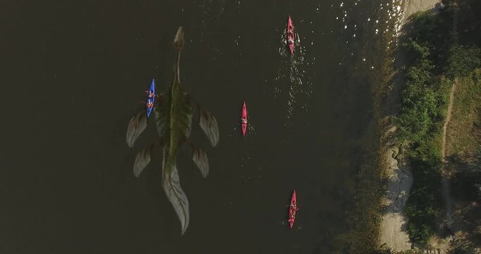 Aerial view. Dragon In muddy water, with poor visibility, monster of prehistoric era, swims underwater next to kayaks on river. Ness Monster
