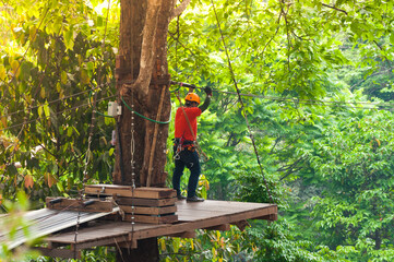 adventure zipline high wire park - people on course in mountain helmet and safety equipment,ready to descend on zipline in forest, extreme sport