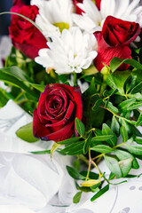 Bouquet of flowers bright red roses and white daisies, macro photo floristry, shop advertising and flower delivery bouquets, rosebud with drops of dew water freshness