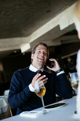 Handsome businessman dressed in the suit drinking wine. Businessman talking to the phone.